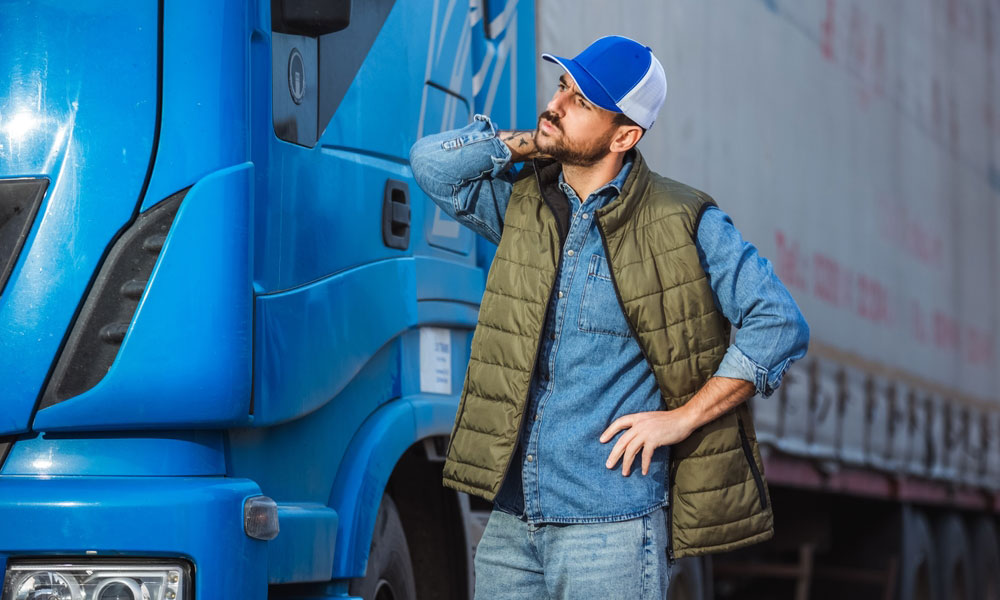 راننده کامیون کنار وسیله نقلیهاش در جادهای بینشهری، نمادی از تلاش ۵۵۲ هزار راننده در حملونقل کالای ایران.